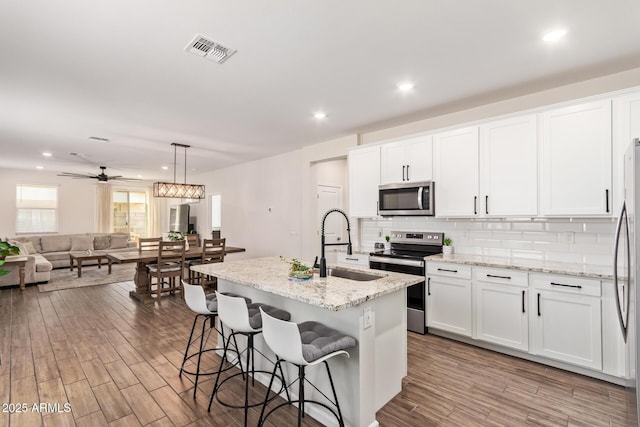 kitchen featuring appliances with stainless steel finishes, wood finished floors, visible vents, and a sink
