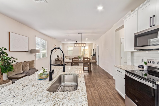 kitchen with stainless steel appliances, backsplash, white cabinets, and a sink