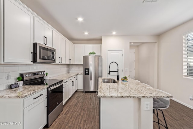 kitchen featuring stainless steel appliances, backsplash, a center island with sink, and a sink