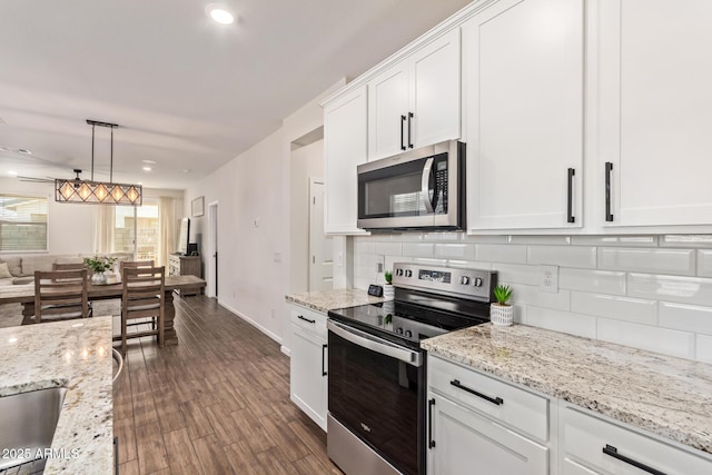 kitchen with light stone countertops, appliances with stainless steel finishes, decorative backsplash, and white cabinetry