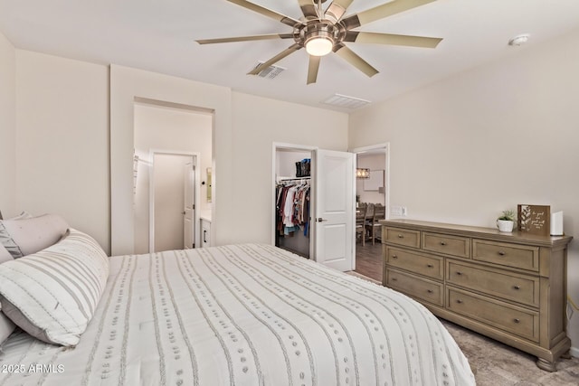 bedroom with visible vents, ensuite bathroom, a closet, a ceiling fan, and a walk in closet