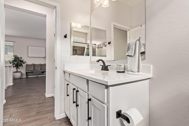 bathroom with wood finished floors, vanity, and baseboards