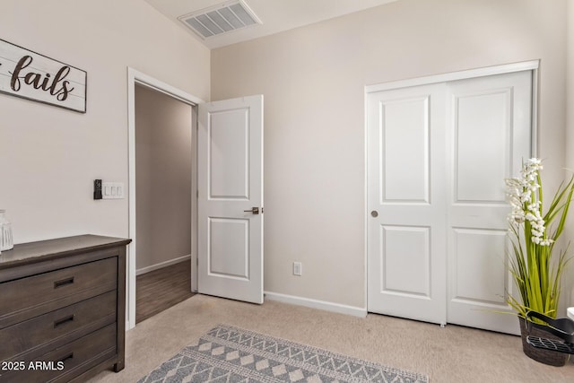 unfurnished bedroom with baseboards, visible vents, a closet, and light colored carpet