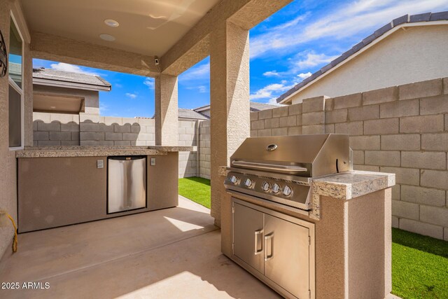 view of patio featuring fence, area for grilling, and exterior kitchen