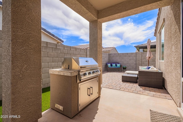 view of patio with outdoor lounge area, fence, grilling area, and exterior kitchen