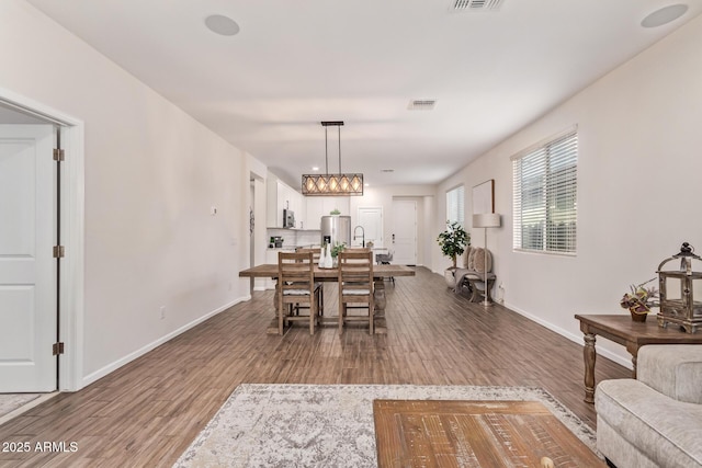 dining space with visible vents, wood finished floors, and baseboards