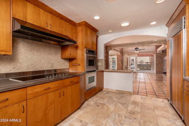 kitchen with appliances with stainless steel finishes, a textured ceiling, ceiling fan, and tasteful backsplash