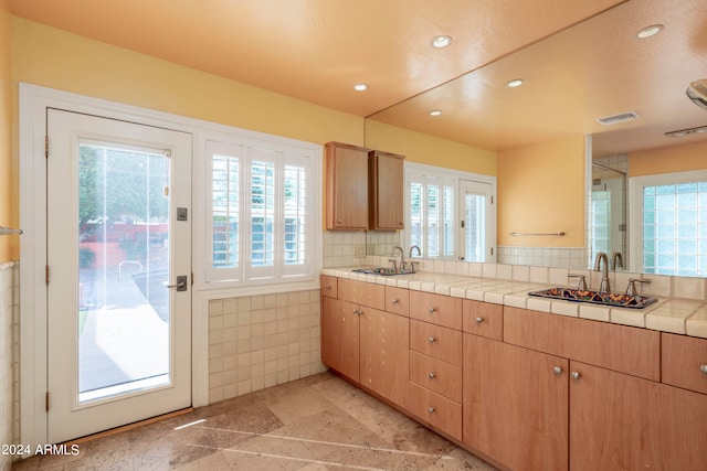 kitchen featuring tile countertops, a healthy amount of sunlight, and sink