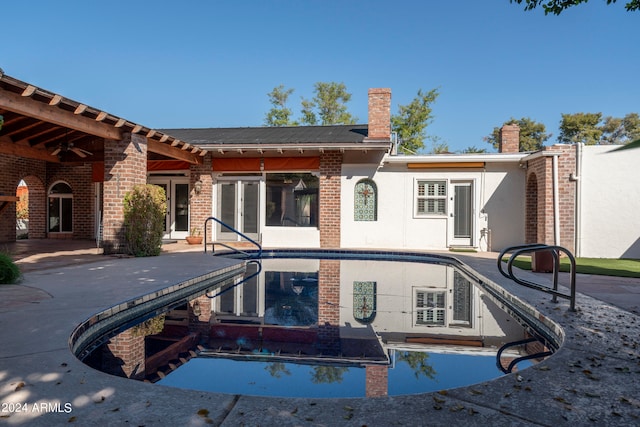 back of property with an empty pool and a patio