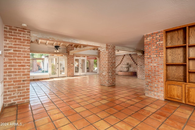 unfurnished living room with ceiling fan, brick wall, beamed ceiling, and light tile patterned floors