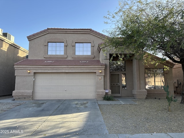 view of front of house with an attached garage, a tiled roof, concrete driveway, and stucco siding