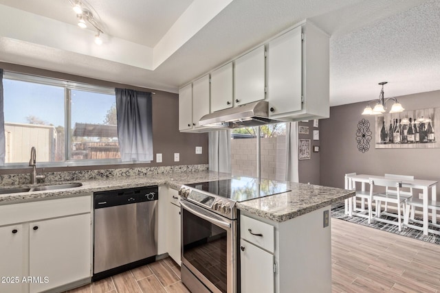 kitchen with sink, appliances with stainless steel finishes, white cabinetry, a textured ceiling, and kitchen peninsula