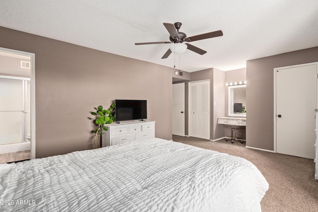 bedroom with ceiling fan, ensuite bathroom, light carpet, and a textured ceiling