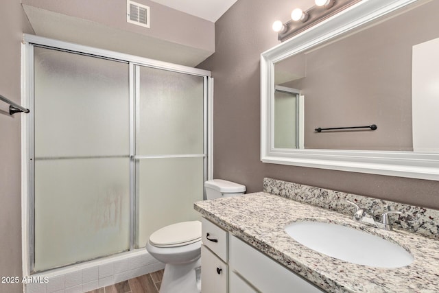 bathroom featuring vanity, hardwood / wood-style floors, an enclosed shower, and toilet