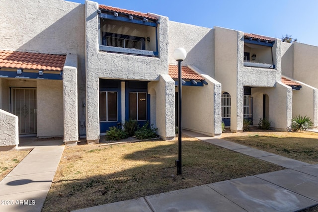 view of front facade featuring a balcony and a front lawn