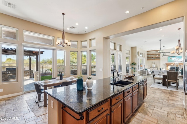 kitchen with dark stone countertops, sink, an island with sink, and pendant lighting