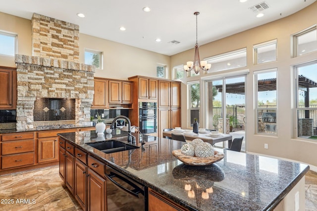 kitchen featuring a notable chandelier, backsplash, a kitchen island with sink, sink, and decorative light fixtures