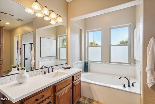 bathroom with vanity, a bathtub, a wealth of natural light, and backsplash