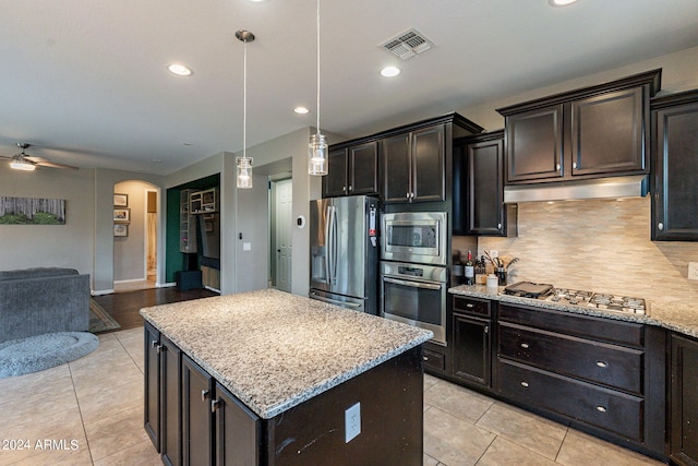 kitchen with appliances with stainless steel finishes, tasteful backsplash, a kitchen island, ceiling fan, and decorative light fixtures