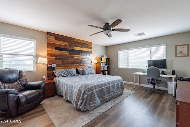 bedroom with multiple windows, wooden walls, dark hardwood / wood-style floors, and ceiling fan