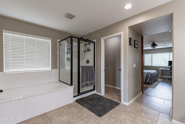 bathroom featuring ceiling fan, plus walk in shower, and tile patterned floors