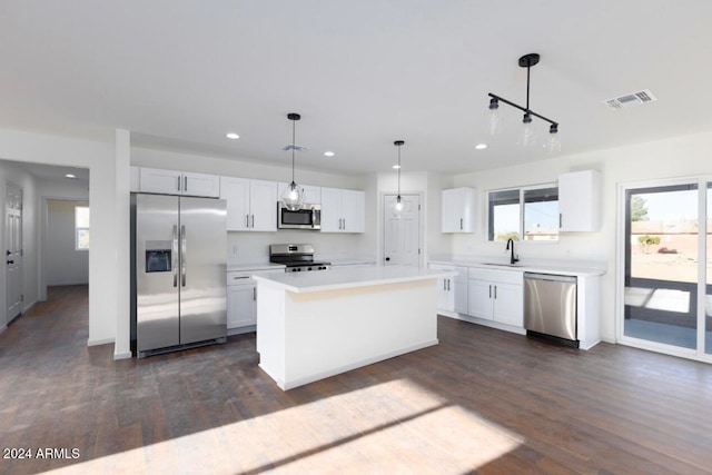 kitchen featuring hanging light fixtures, dark hardwood / wood-style floors, a kitchen island, white cabinetry, and stainless steel appliances