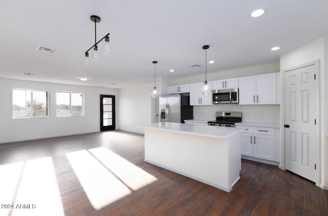 kitchen featuring dark hardwood / wood-style flooring, stainless steel appliances, pendant lighting, a center island, and white cabinetry