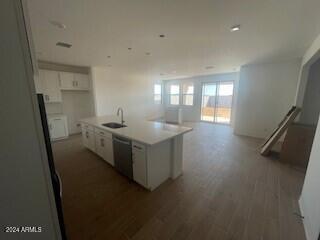 kitchen with dishwasher, hardwood / wood-style floors, a center island with sink, sink, and white cabinetry