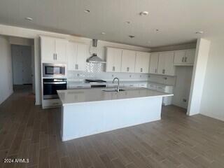 kitchen with white cabinets, appliances with stainless steel finishes, a kitchen island with sink, and sink