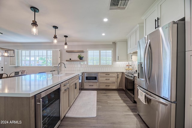 8049 N 16th Ave, Phoenix, AZ 85021 - kitchen featuring stainless steel appliances, beverage cooler, a sink, crown molding, and backsplash