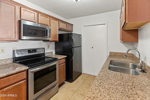 kitchen featuring light stone counters, sink, light tile patterned floors, and appliances with stainless steel finishes