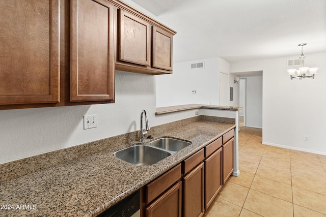 kitchen featuring pendant lighting, sink, dark stone countertops, light tile patterned floors, and a notable chandelier