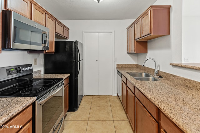 kitchen featuring appliances with stainless steel finishes, light stone counters, light tile patterned floors, and sink