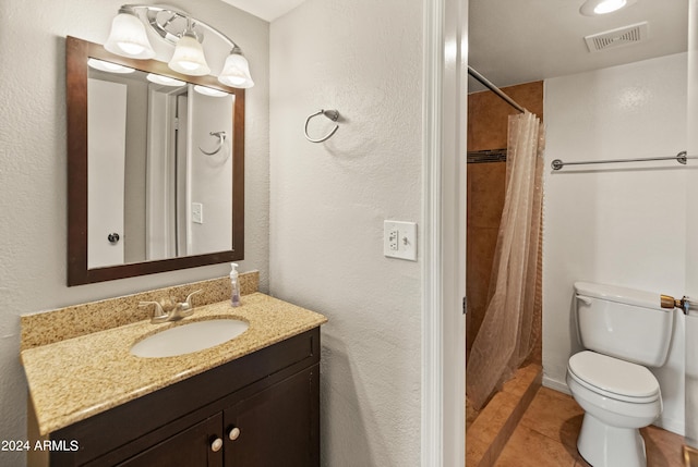 bathroom featuring tile patterned flooring, vanity, toilet, and walk in shower