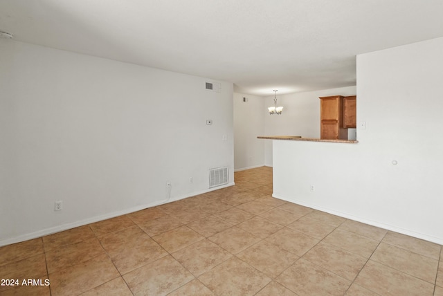 spare room featuring light tile patterned flooring and a notable chandelier