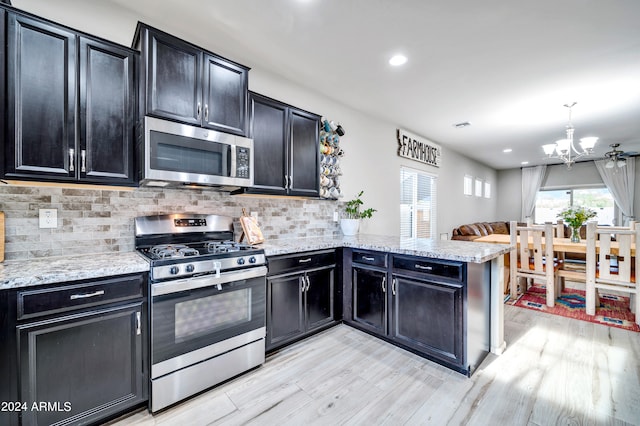 kitchen featuring light wood-type flooring, stainless steel appliances, and kitchen peninsula