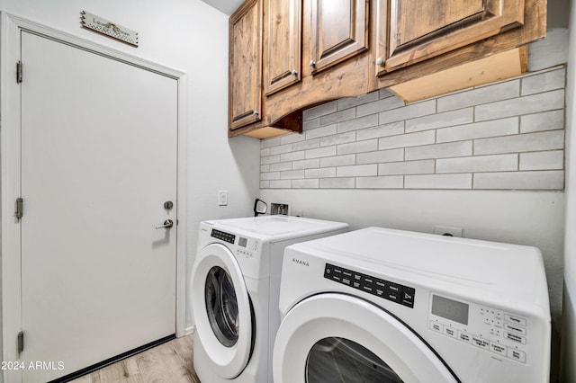 laundry area with independent washer and dryer, light hardwood / wood-style flooring, and cabinets