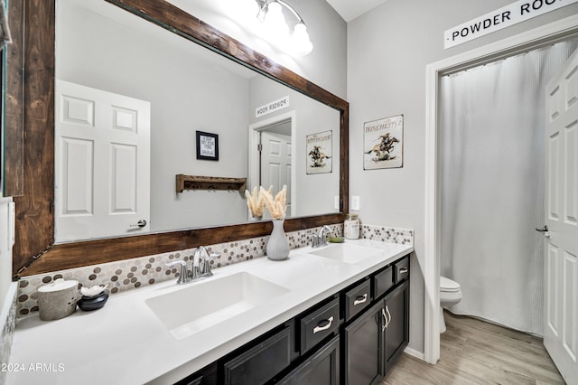 bathroom with dual vanity, toilet, and hardwood / wood-style floors