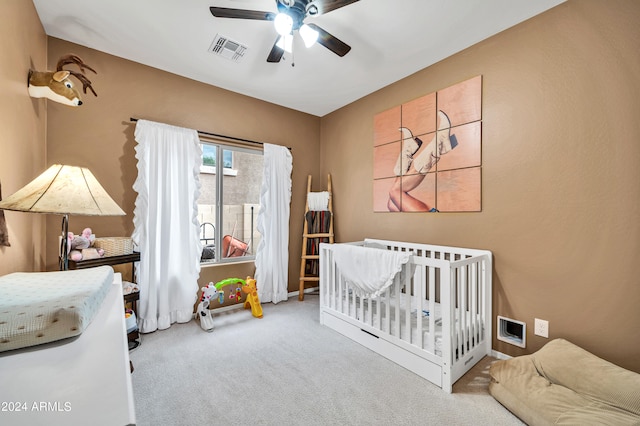 bedroom featuring ceiling fan, light colored carpet, and a nursery area