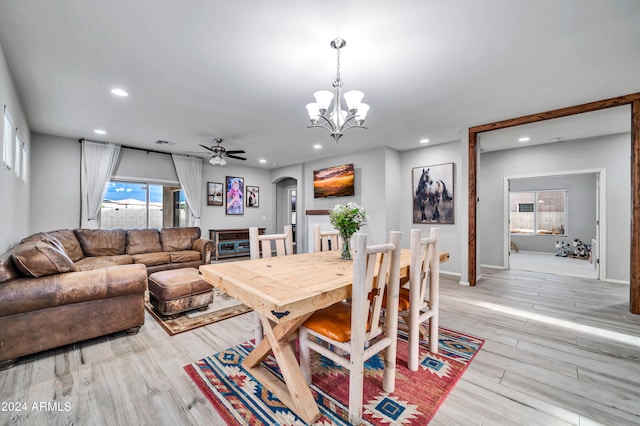 dining area with light wood-type flooring and ceiling fan with notable chandelier