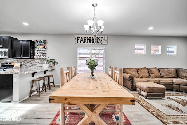 dining area with a notable chandelier, light wood-type flooring, and plenty of natural light