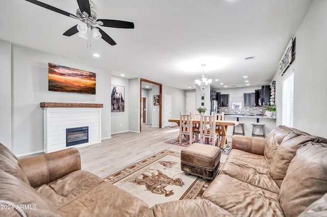 living room featuring ceiling fan with notable chandelier and light hardwood / wood-style flooring