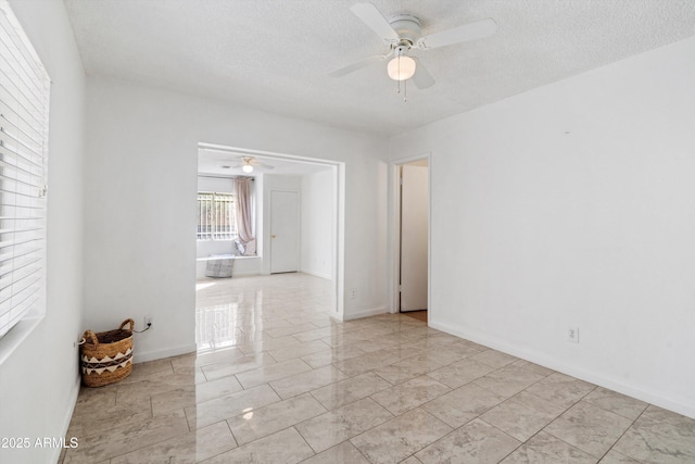 empty room with ceiling fan and a textured ceiling