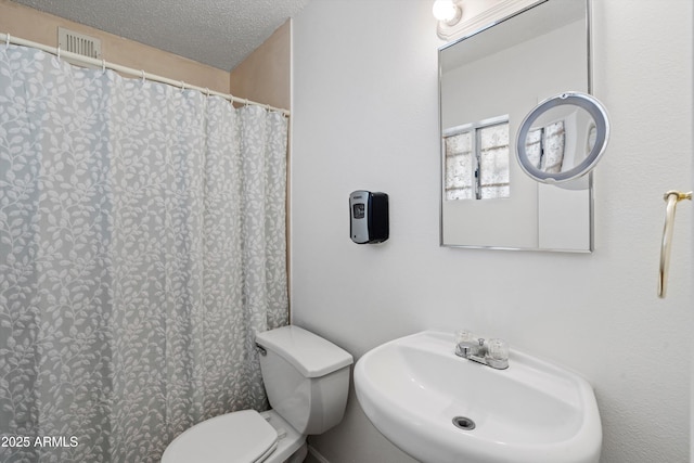 bathroom with toilet, sink, and a textured ceiling