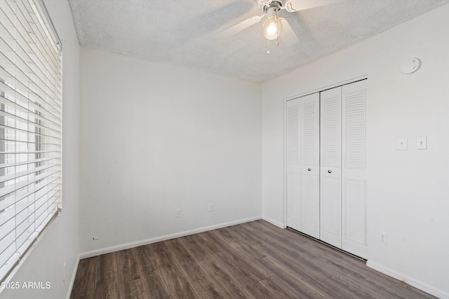 unfurnished bedroom featuring dark wood-type flooring, a textured ceiling, and a closet