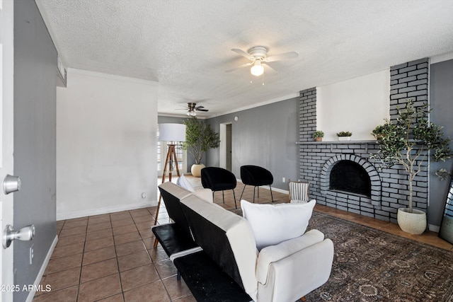 living room with a brick fireplace, dark tile patterned floors, a textured ceiling, and ceiling fan