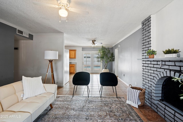 living room with tile patterned floors, crown molding, a brick fireplace, a textured ceiling, and ceiling fan