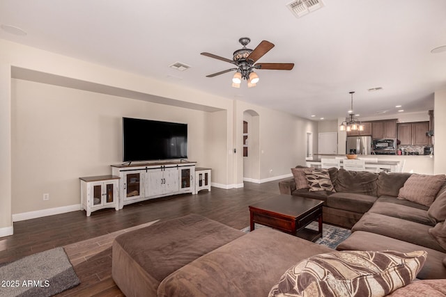 living room featuring ceiling fan with notable chandelier and dark hardwood / wood-style flooring