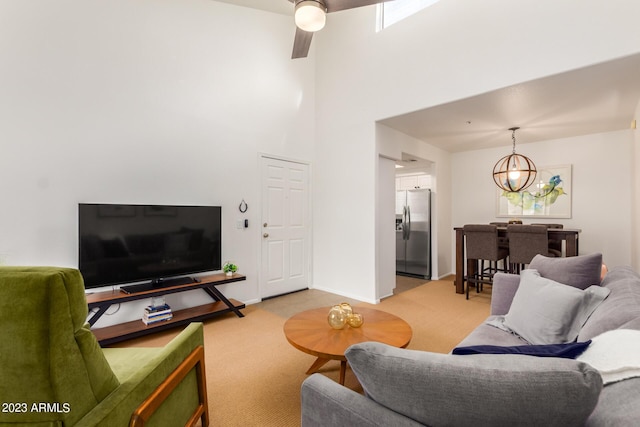 living area featuring light carpet, a towering ceiling, baseboards, and a notable chandelier