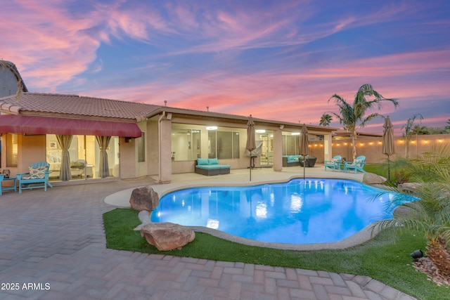 pool at dusk featuring a patio